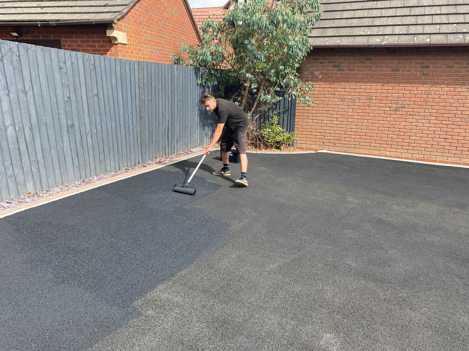 Applying tarmac recolouring coating by roller in Staffordshire